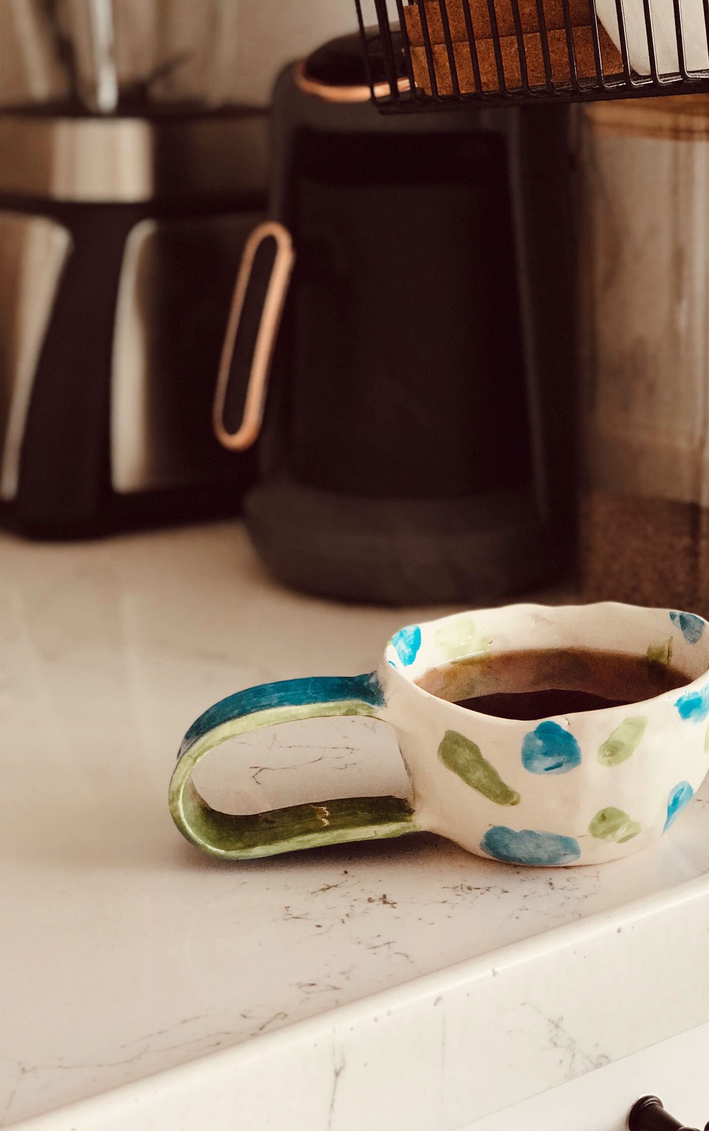 Unedited snapshot of a handmade ceramic mug on a cluttered kitchen counter